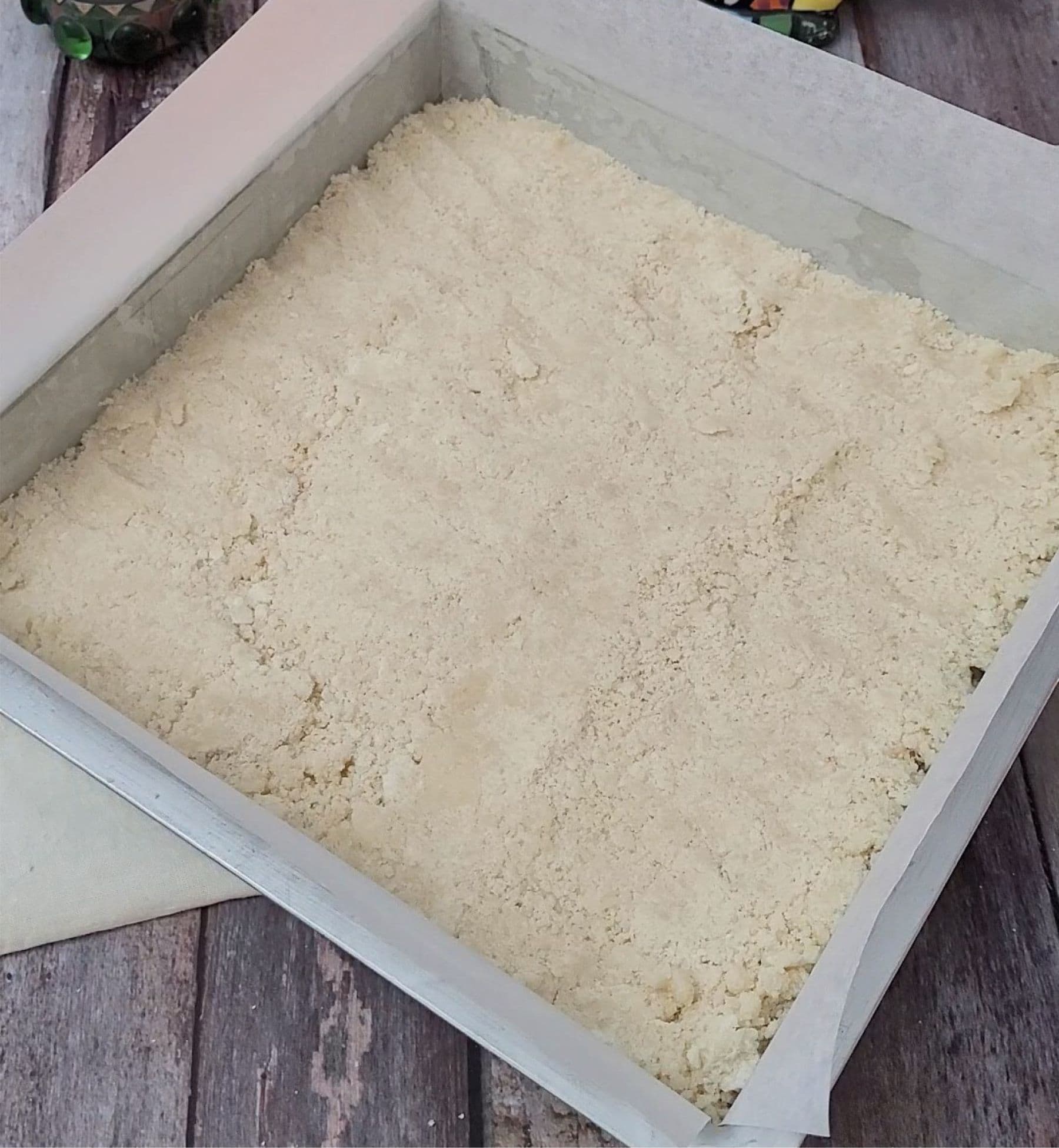 press shortbread base into pan for first bake of chocolate coconut cookie bars