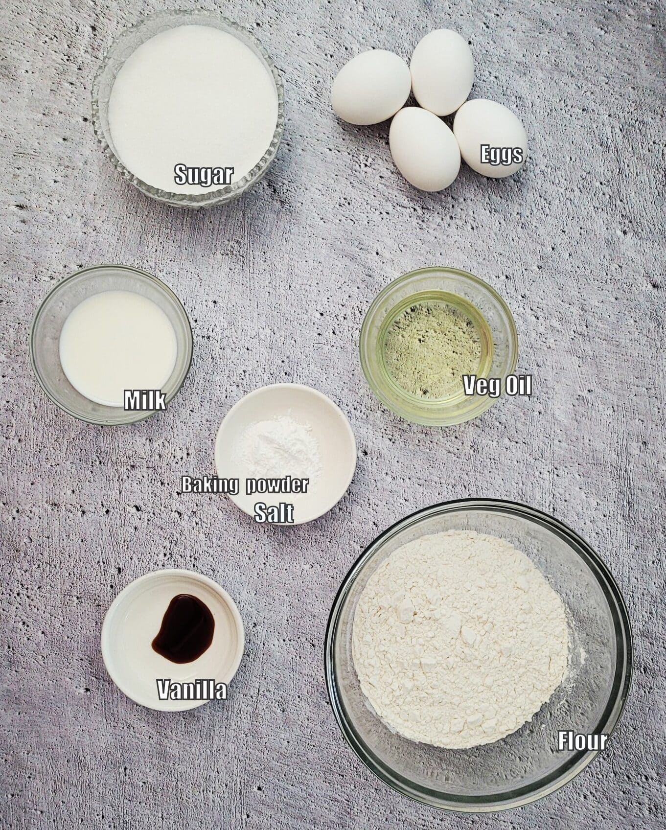 ingredients for vanilla cake including flour, sugar, baking powder, salt, vanilla bean paste, eggs, milk and oil