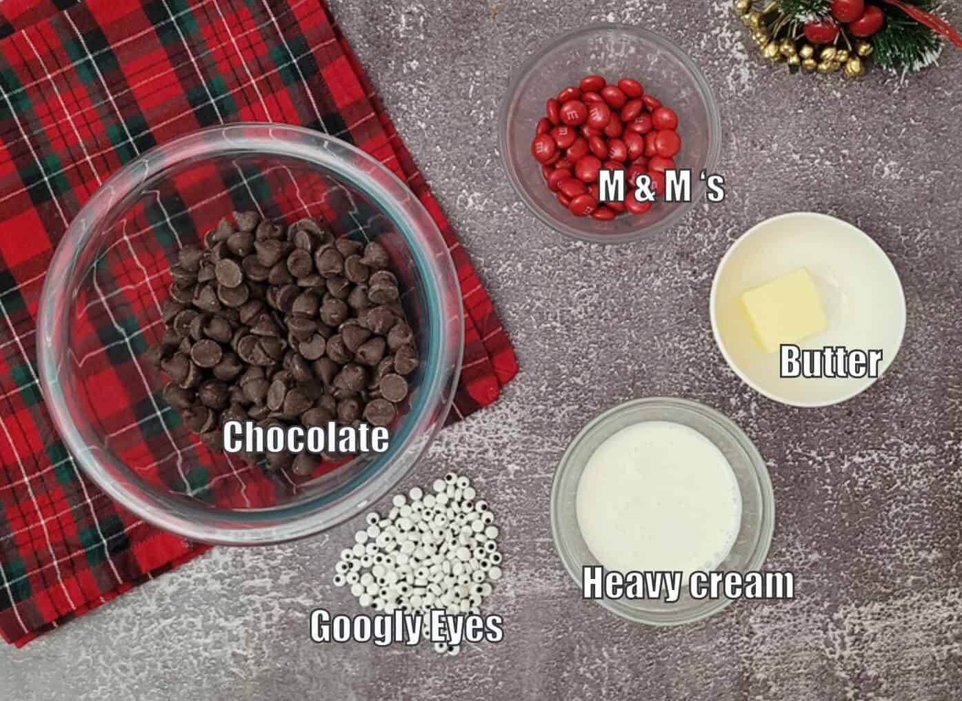 ingredients needed for the top of reindeer shortbread caramel bars including chocolate, cream, googly eyes, butter and M&Ms