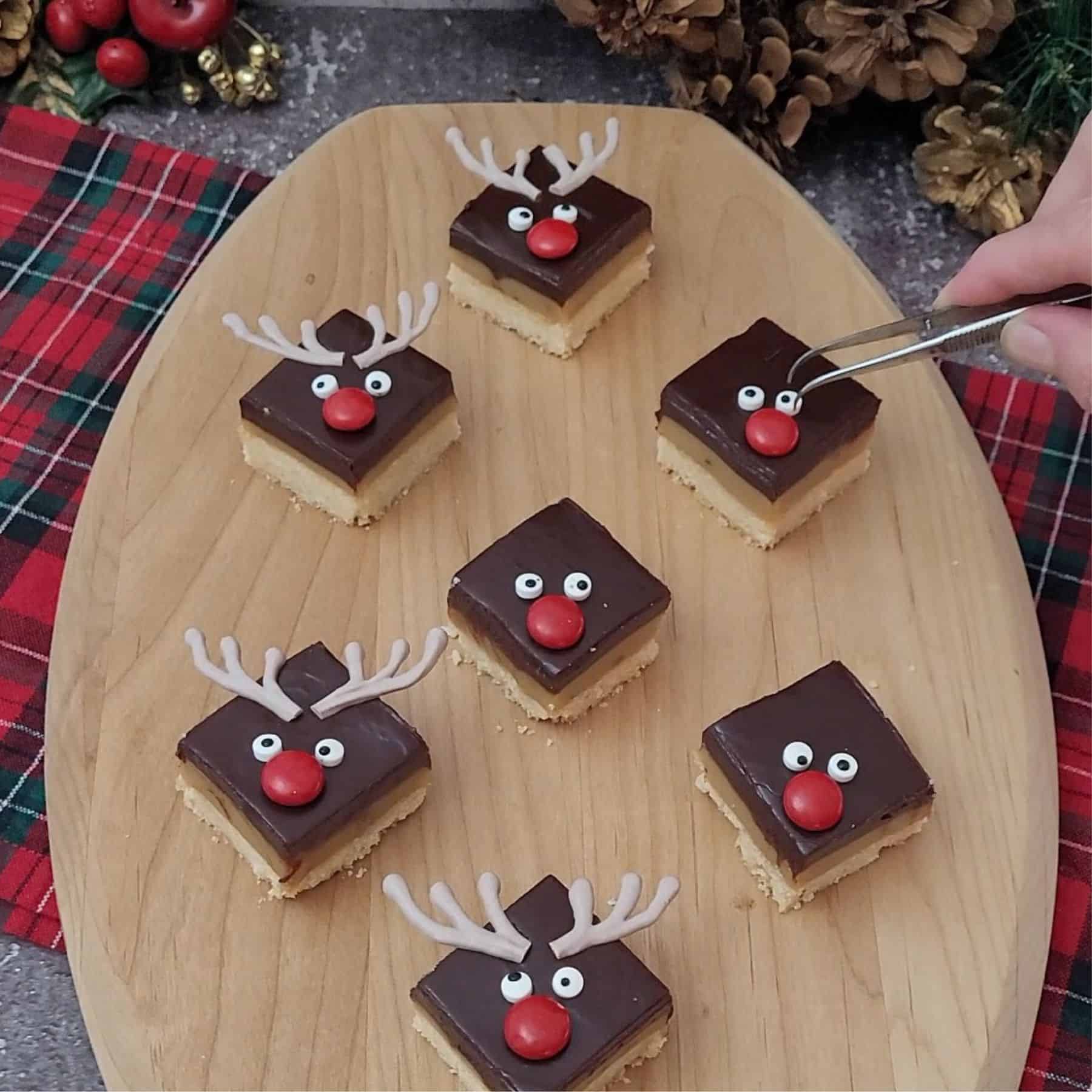 adding decorations to top of Christmas shortbread reindeer bars