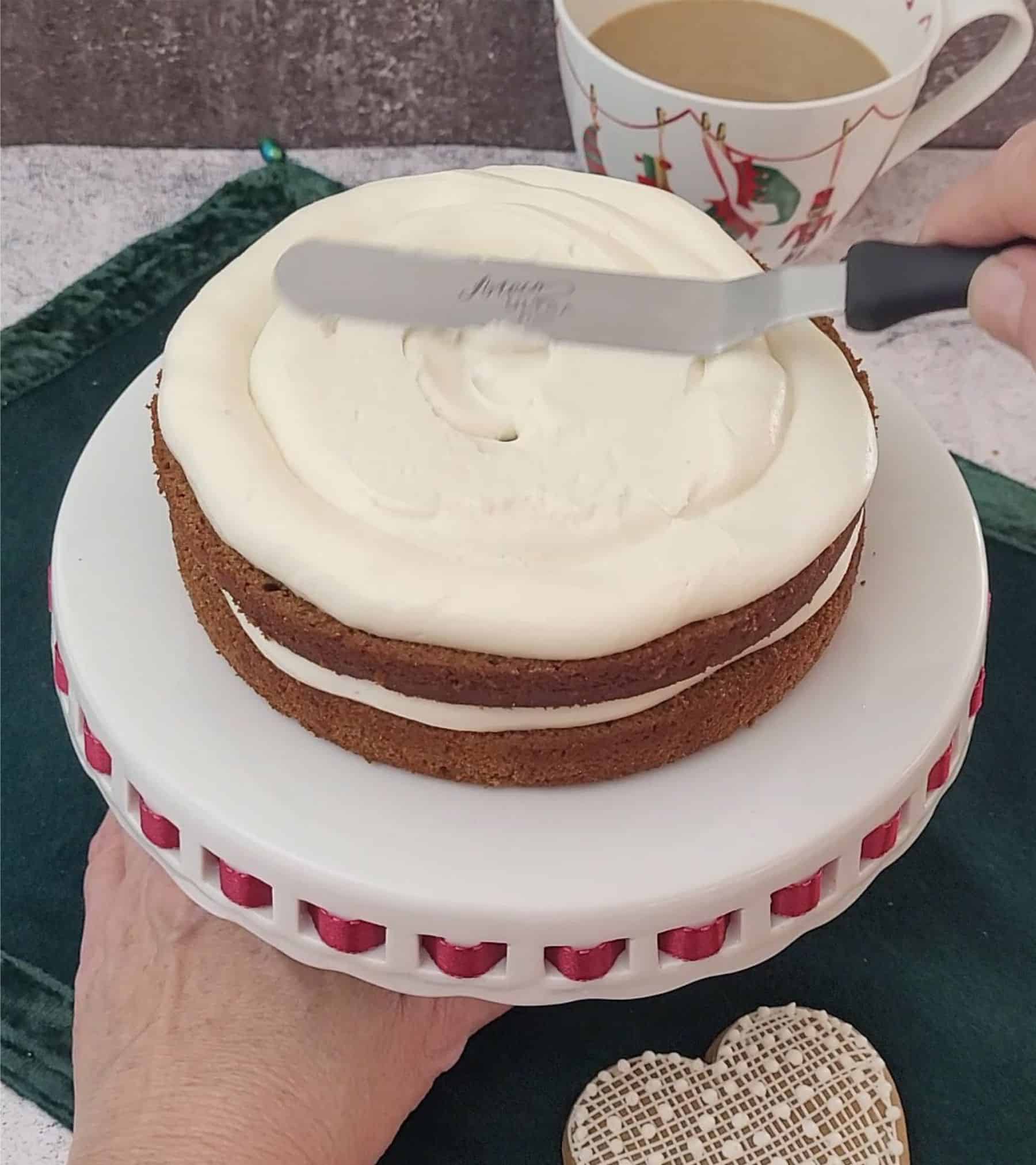 spreading cream cheese filling on second layer of holiday gingerbread cake