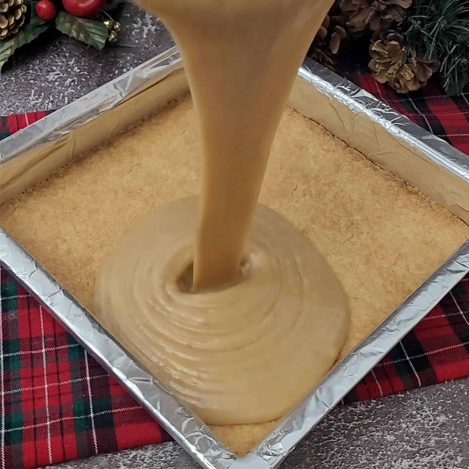 pouring caramel over baked shortbread