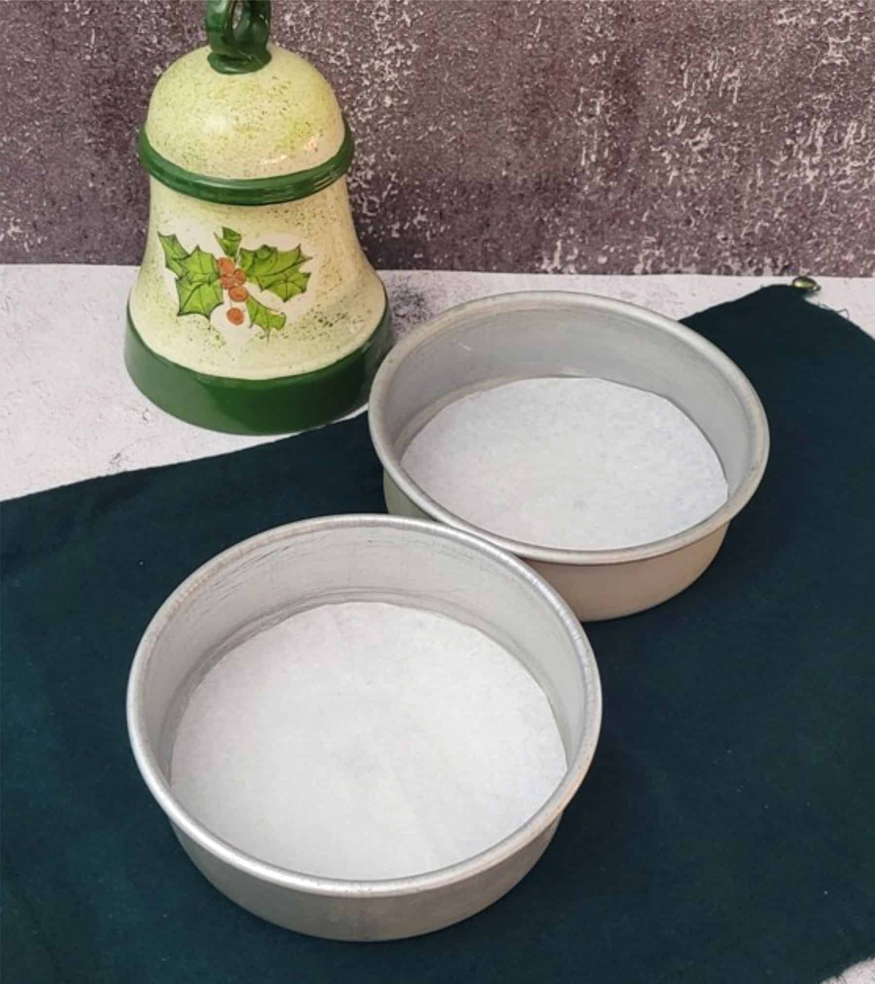 two six inch cake pans prepared with parchment paper to ready for making a holiday gingerbread cake