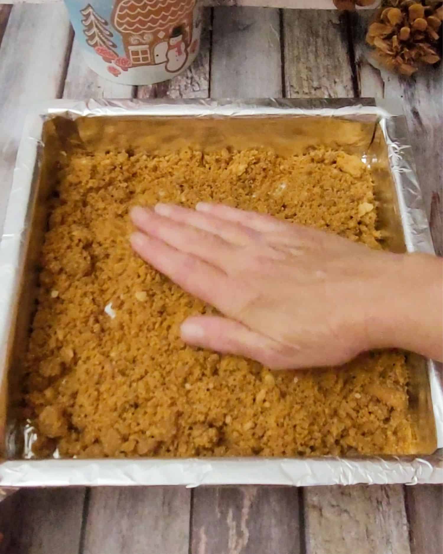 pressing gingersnap cookie crust into square pan to make a base for fudge topping