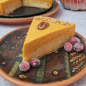 slice on cake on a plate decorated with candied cranberries and a toasted pecan