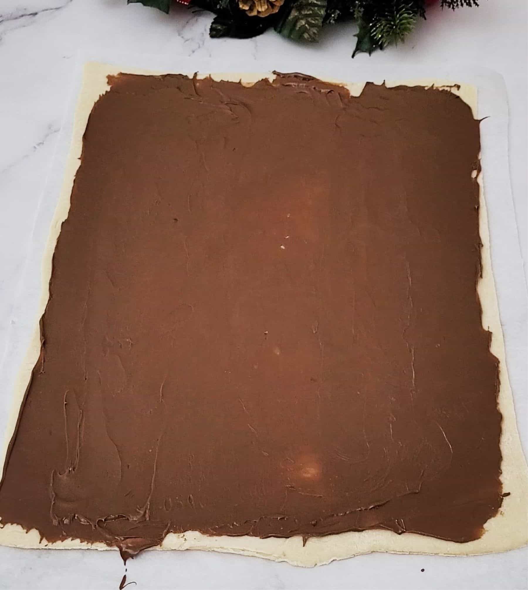 step to make puff pastry Nutella Christmas tree by spreading Nutella on first sheet