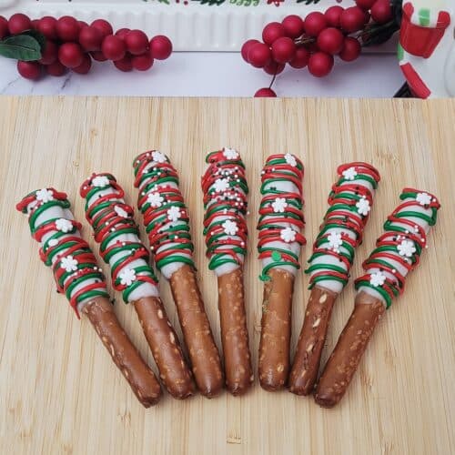 Christmas pretzel rods with caramel and white coating on a wooden platter