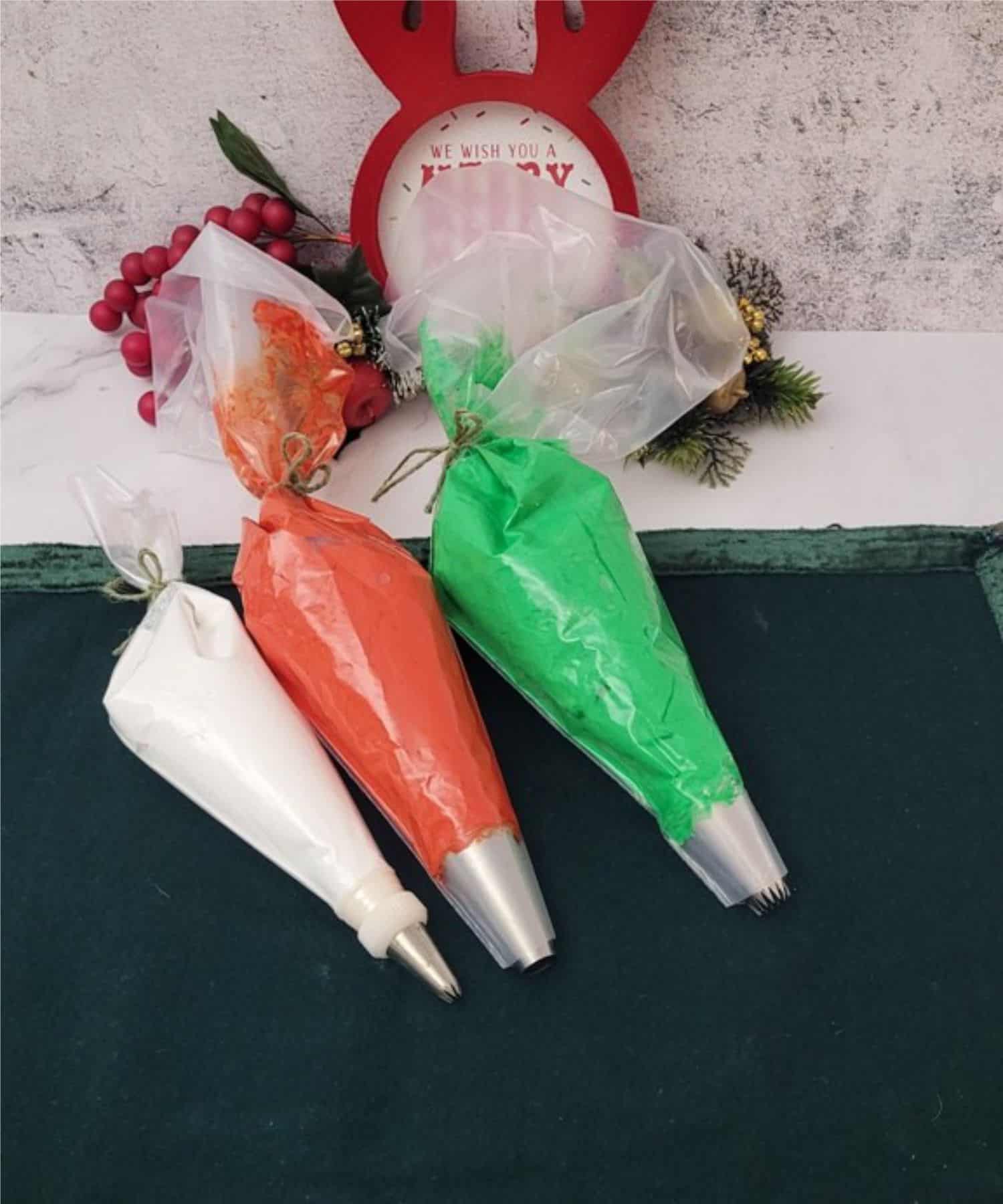 three piping bags filled with meringue one with white, one with red and one with green