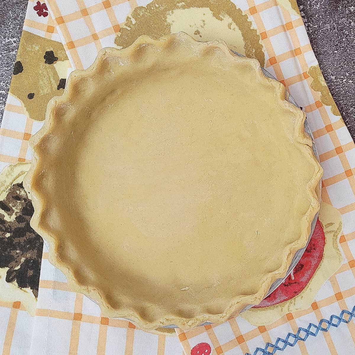 overhead view of Gluten free pie crust in a pan with the edges of crust fluted