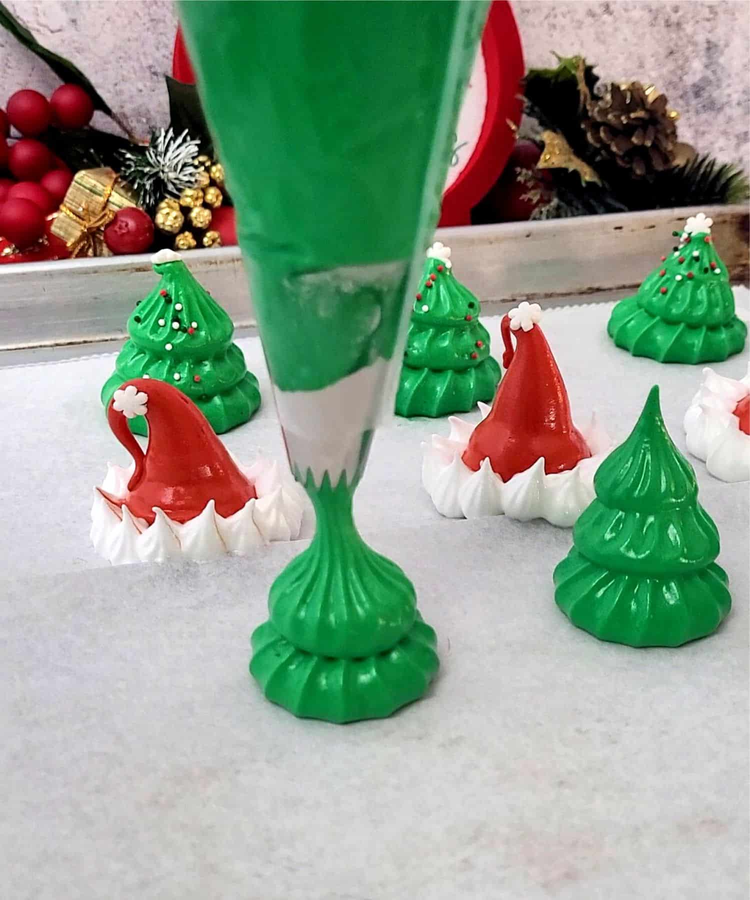 using green meringue to pipe Christmas tree shaped cookies onto a baking pan