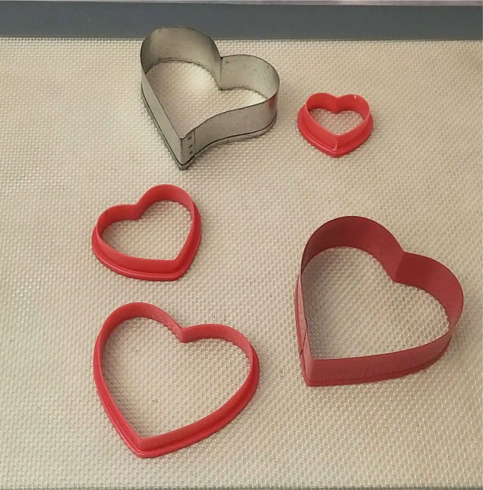 pan prepared to with a silicone mat and heart shaped cookie cutters to make Valentines chocolate bark recipe