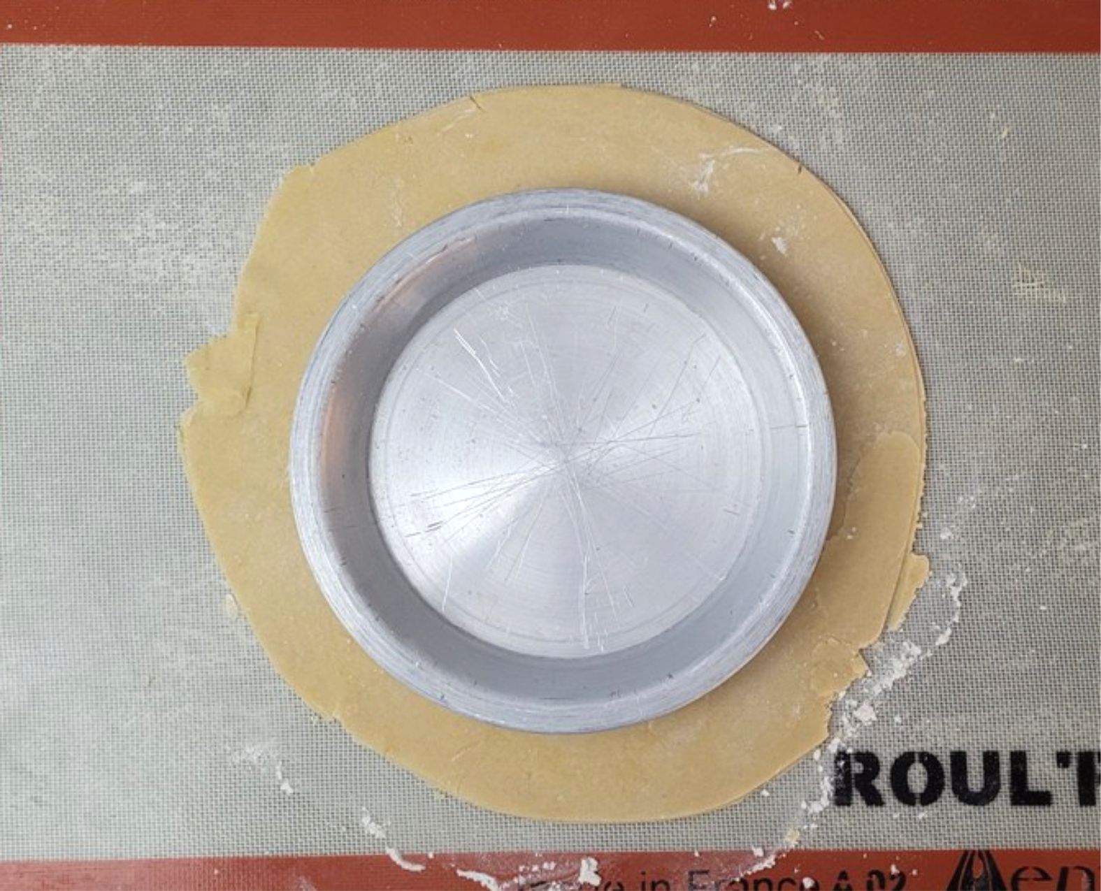 dough rolled into a circle with a pie tin to check for correct size