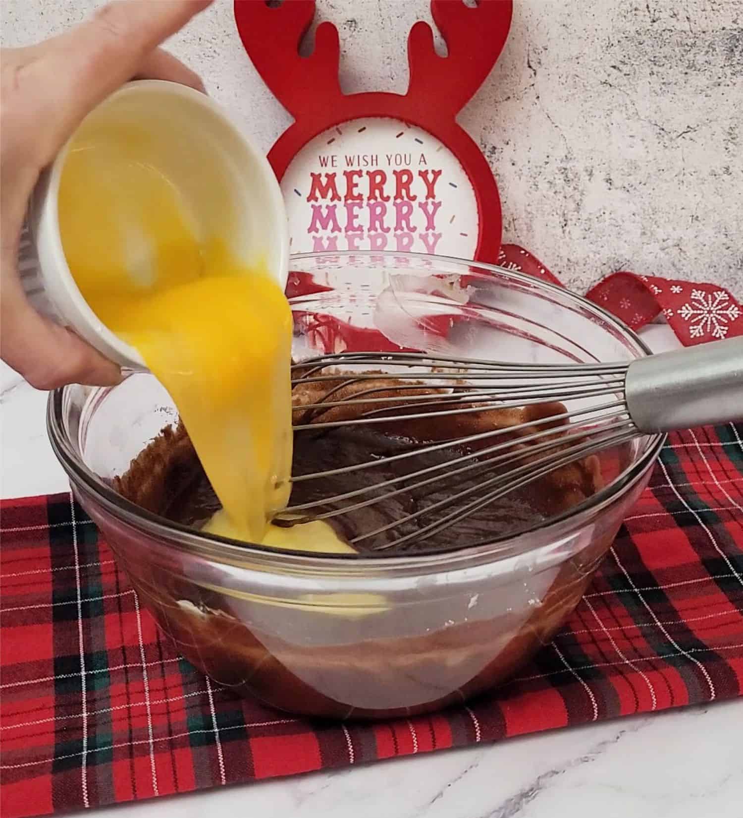 adding eggs to mixing bowl