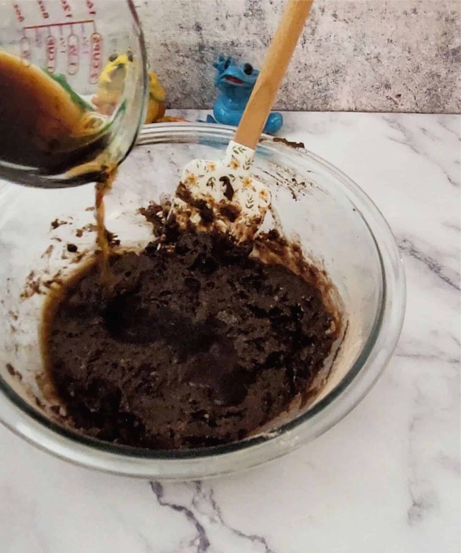 pouring coffee into mixing bowl to make chocolate batter for banana upside down cake