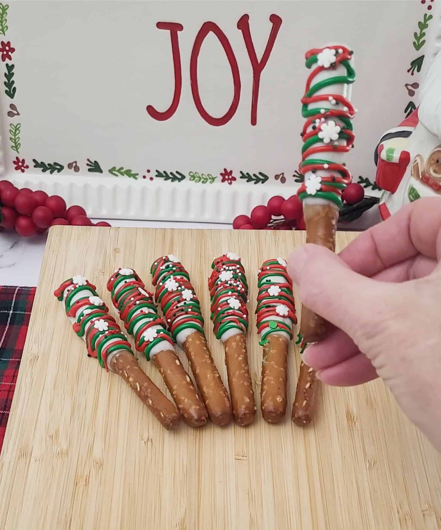 holding up one Christmas pretzel rod with caramel