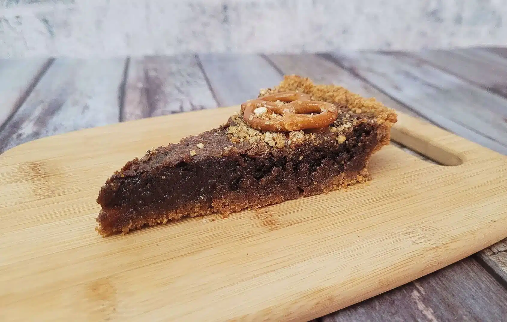 slice of a chocolate pretzel tart on a wooden dish