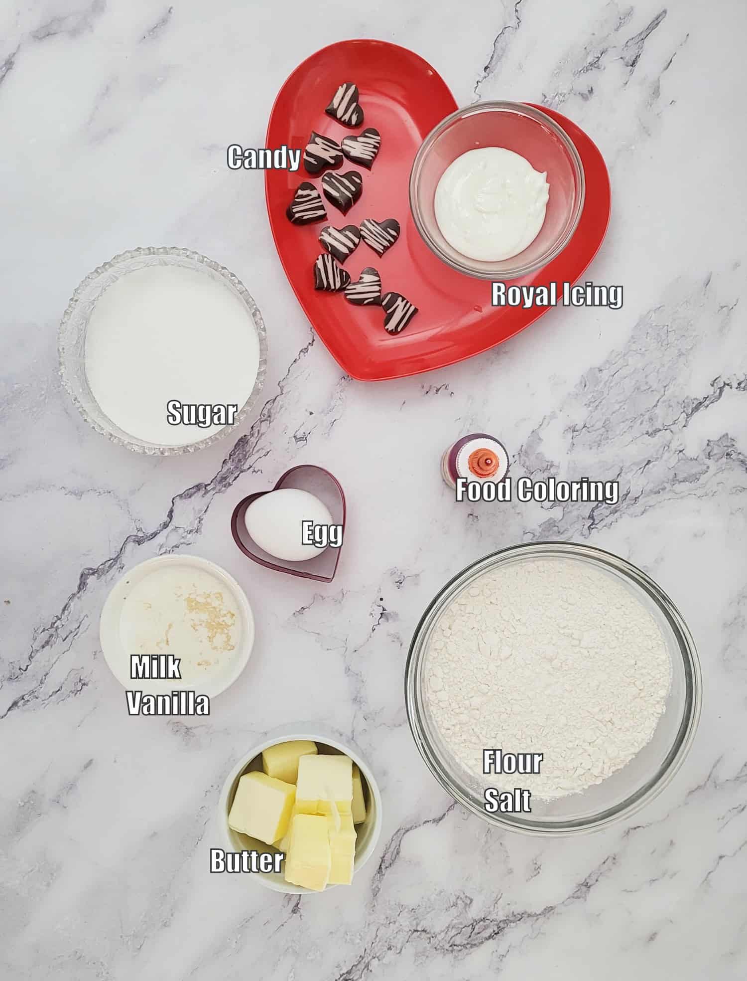 ingredients needed to make Valentine Butter Cookies including flour, salt sugar, vanilla, milk, egg, food coloring, chocolate hearts and royal icing