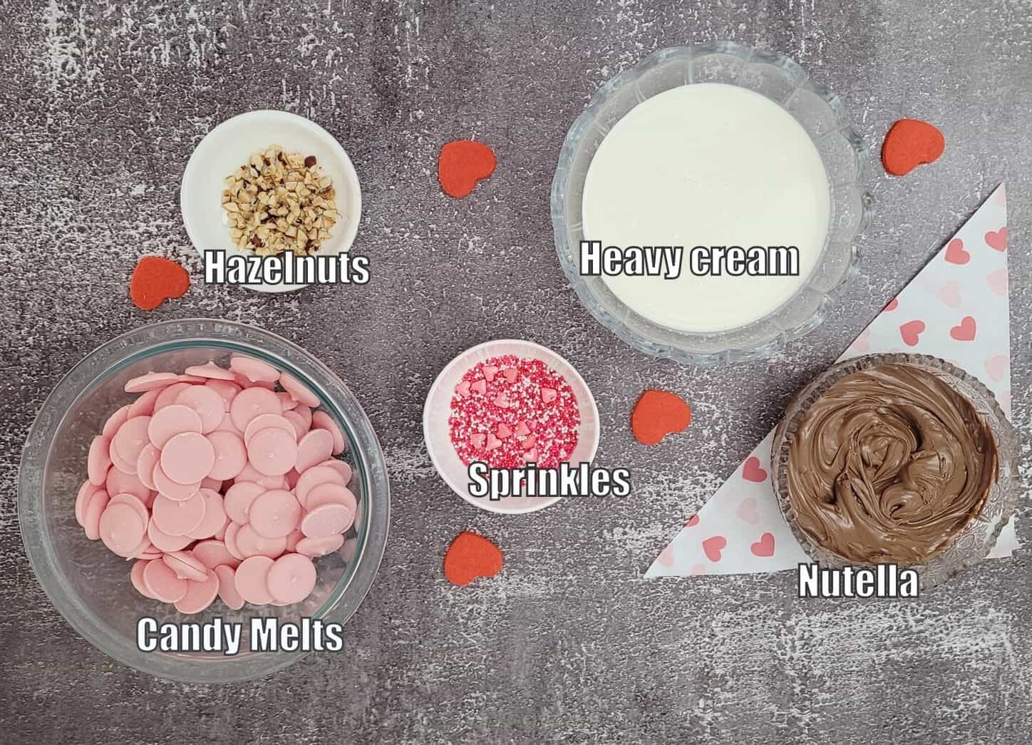 ingredients needed to make Valentines Nutella mousse bombs including pink candy melts, sprinkles, hazelnuts, heavy cream and Nutella