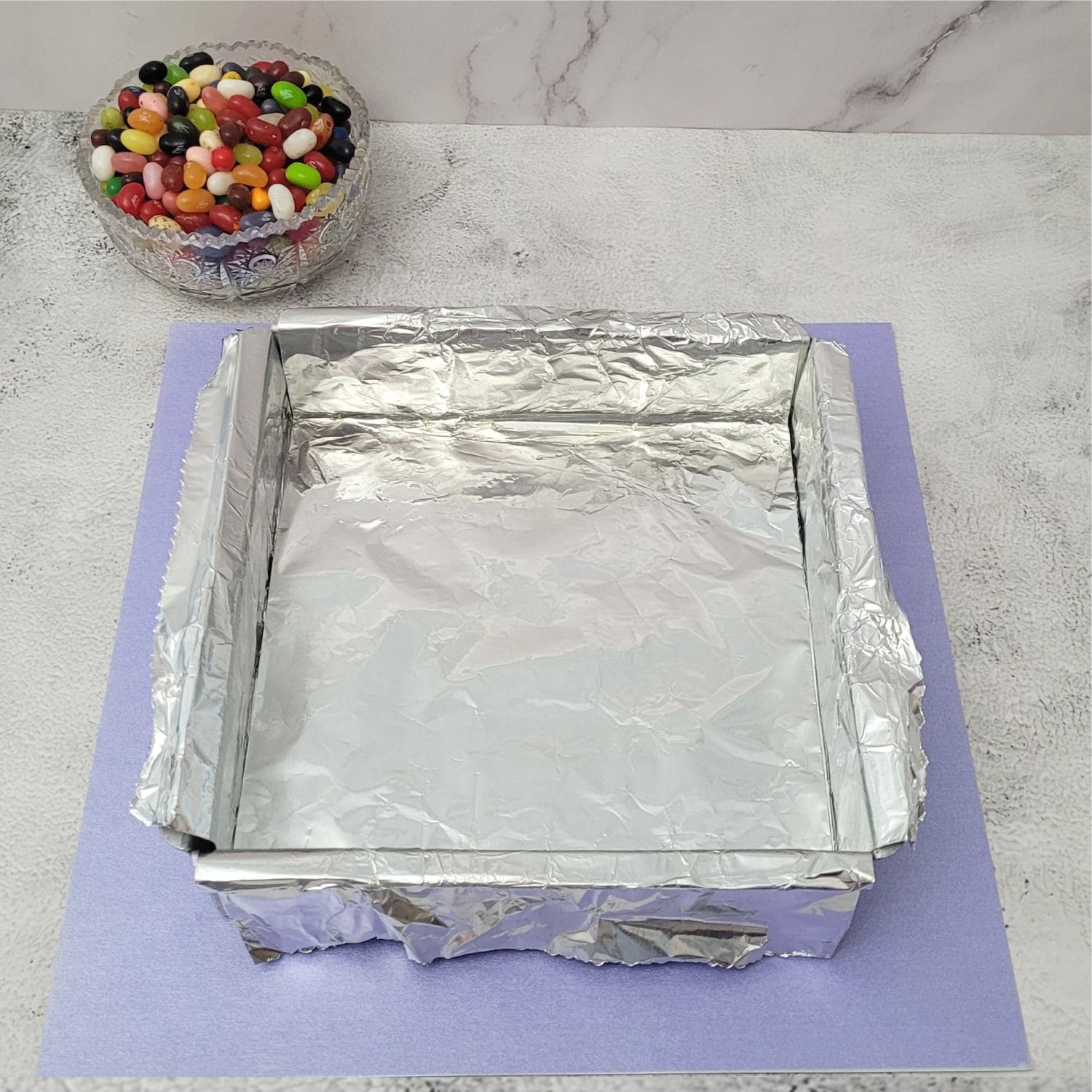 square pan lined with foil to prepare for making Easter jelly bean fudge