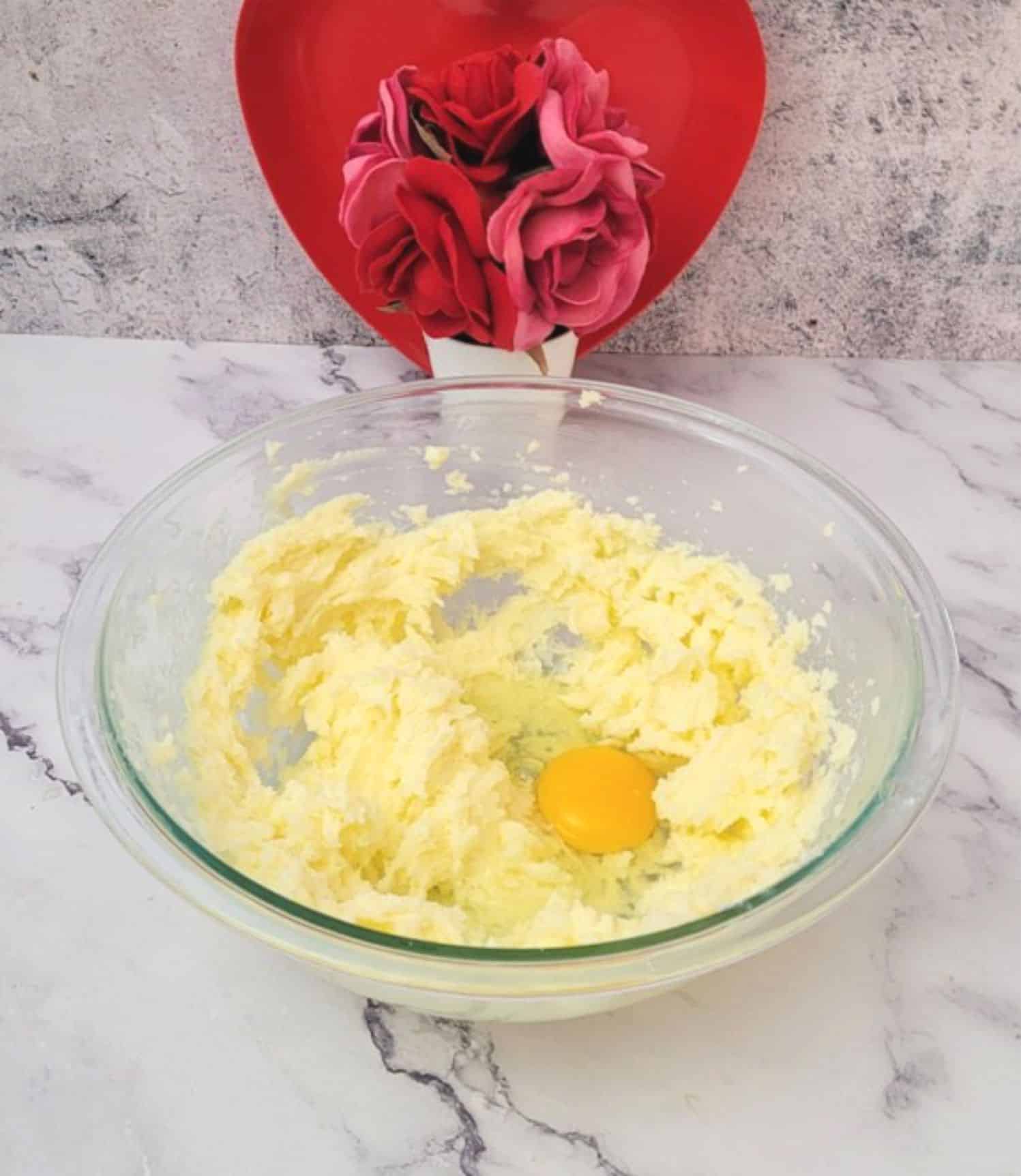 first step in making Valentine Bear Cookies by creaming together butter and sugar then adding an egg