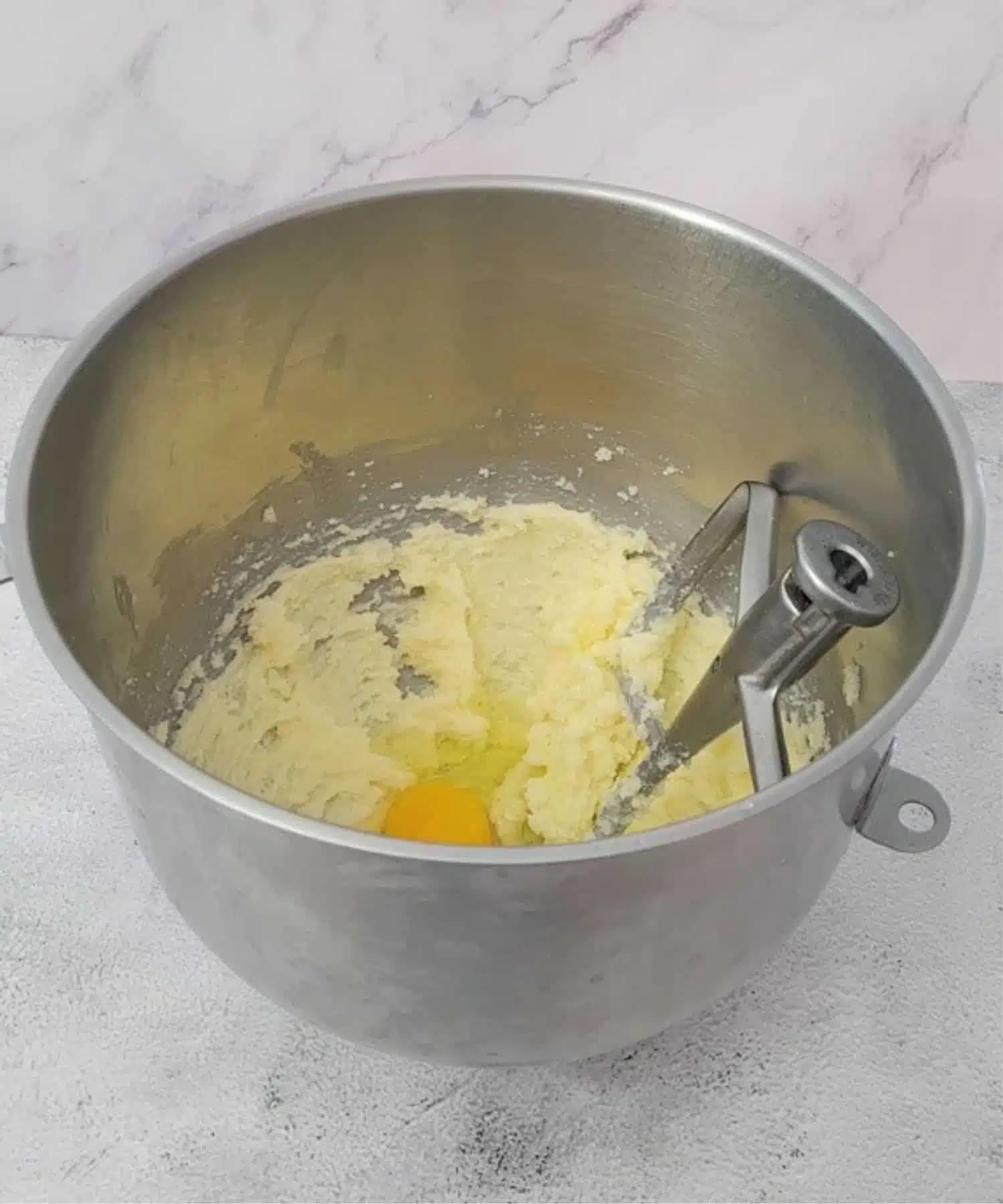 butter and sugar mixed together in a mixing bowl and an egg added to bowl