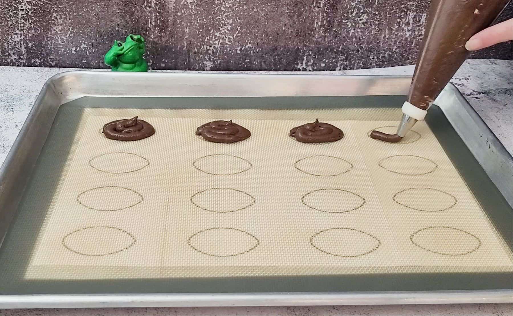 piping whoopie pie batter in the shape of footballs onto a sheet pan