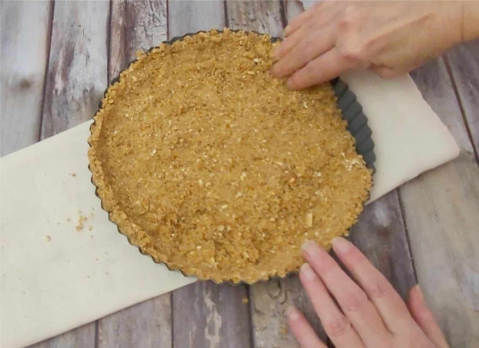 pressing dough into pan to make a chocolate tart with a pretzel crust