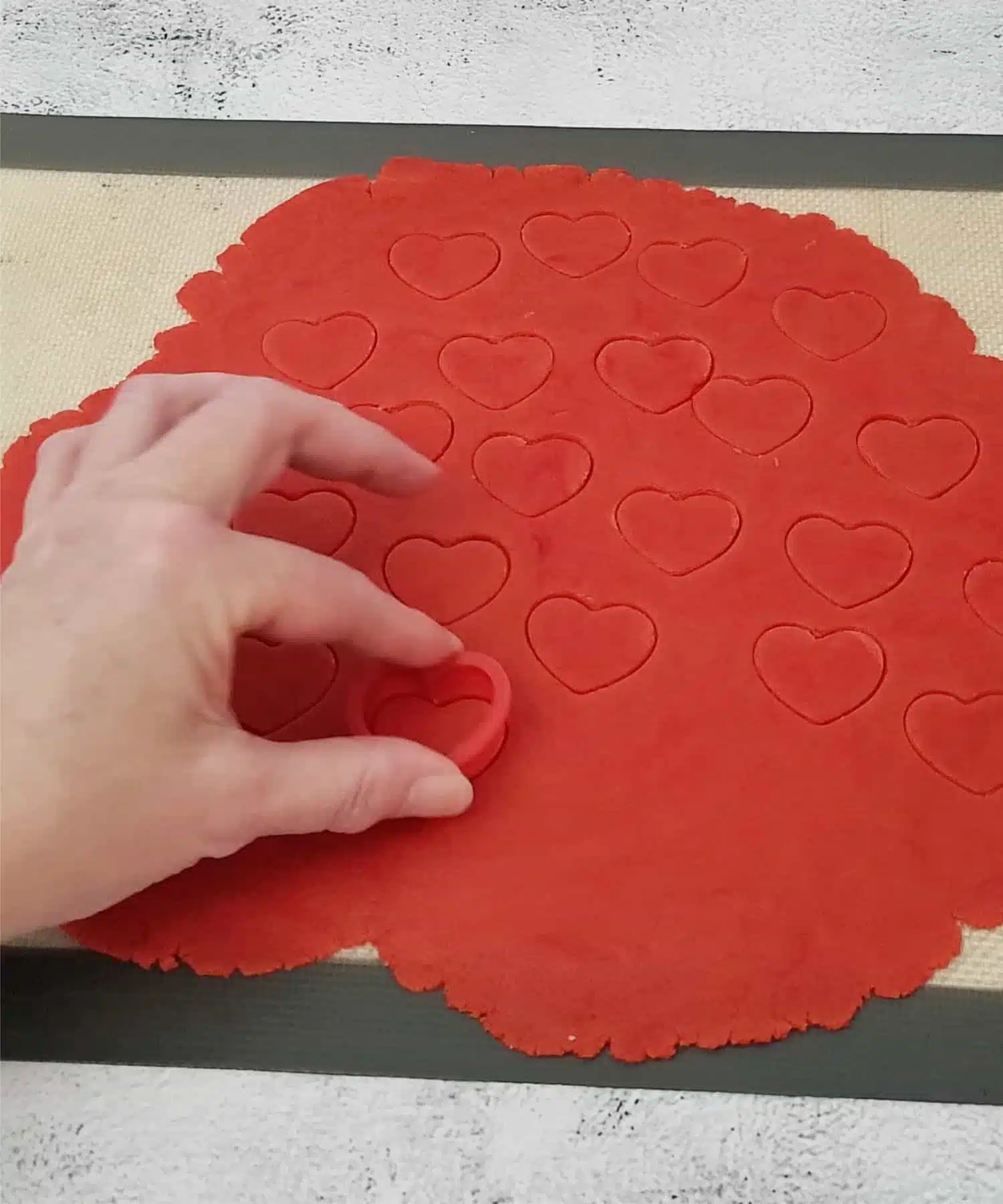 cutting out red hearts from cookie dough