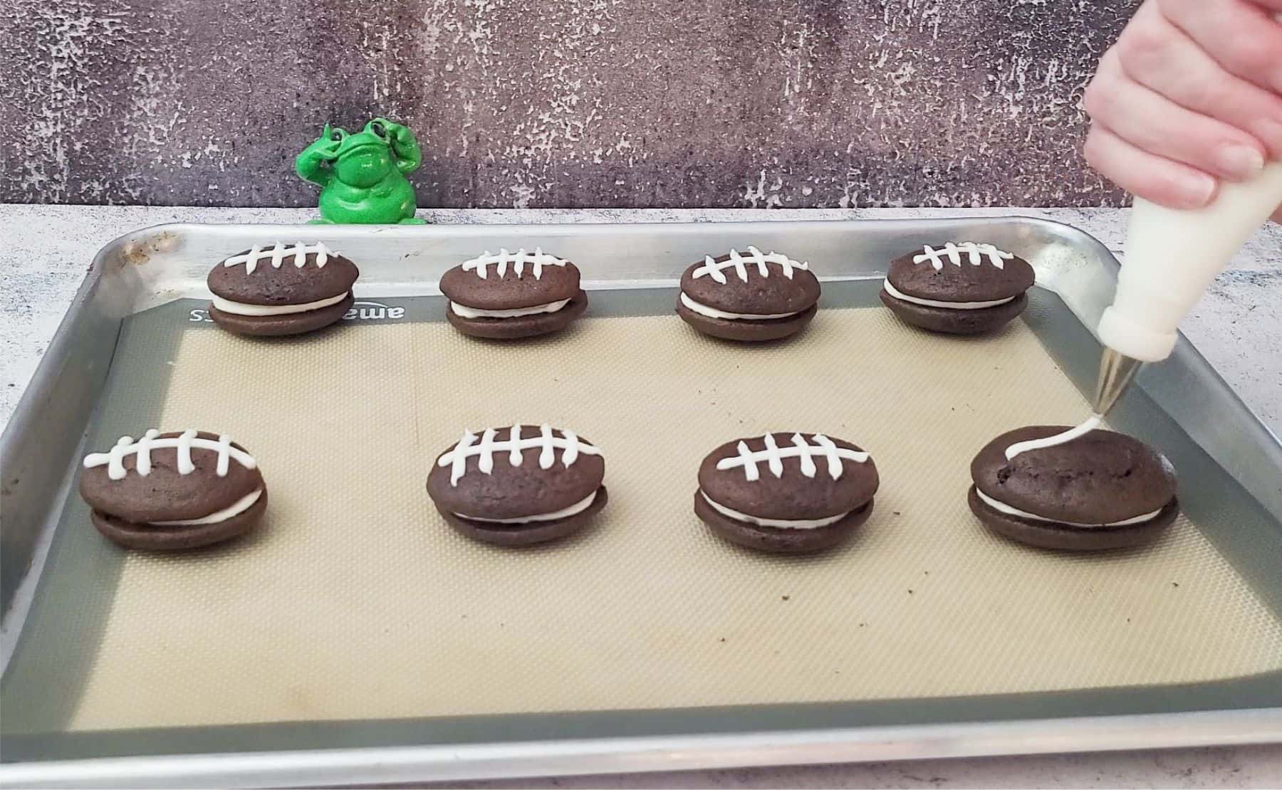 piping football laces onto chocolate whoopie pies