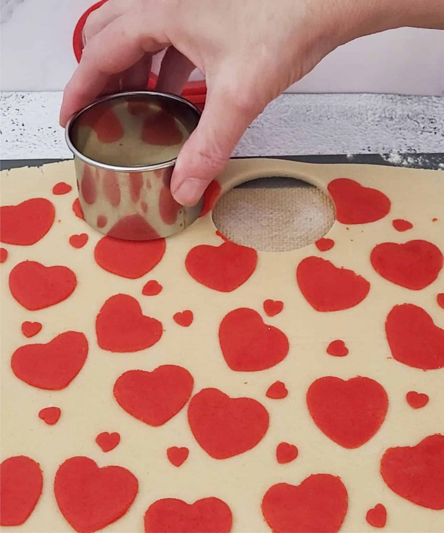 using a round cookie cutter to cut out heart inlay sandwich cookies