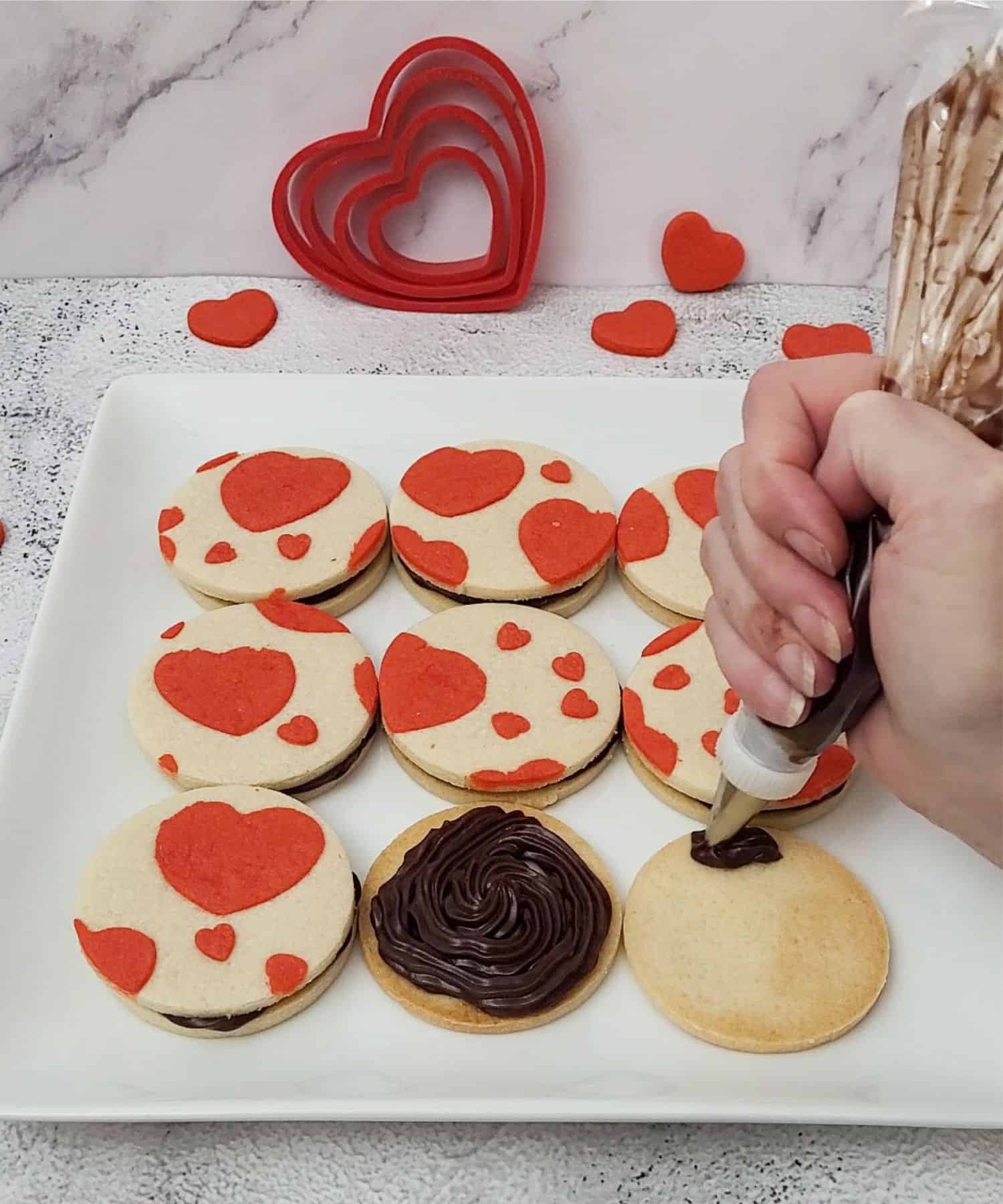 piping fudge filling onto bottom cookies for sandwiching