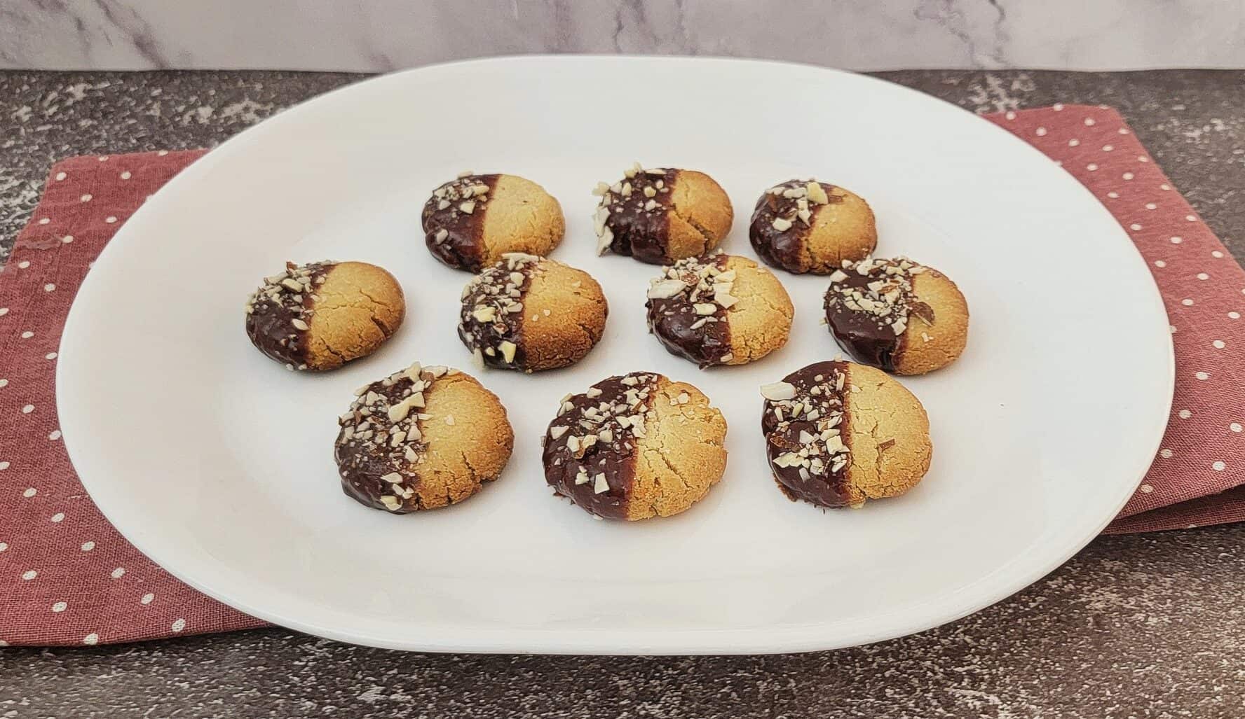 almond flour cookies dipped in chocolate and sprinkled with almonds on a serving platter