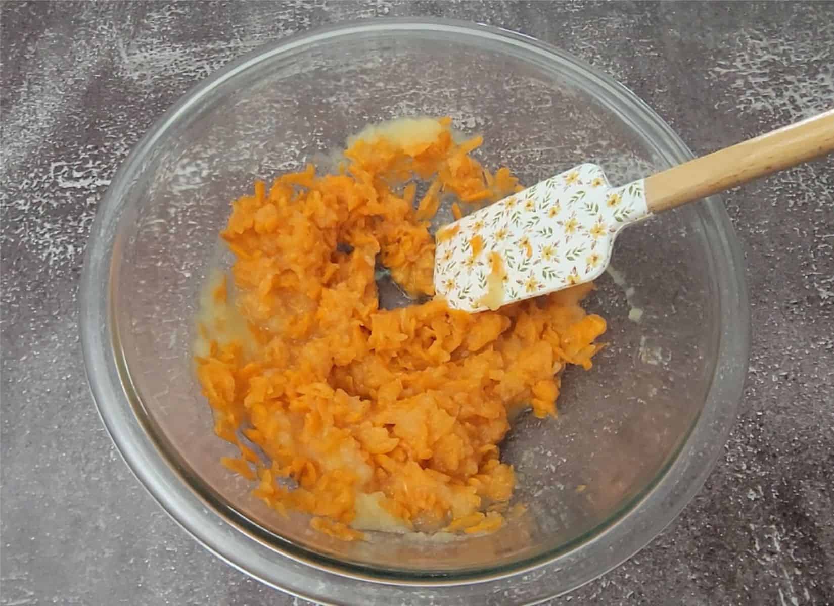 combining applesauce and shredded carrots in a mixing bowl