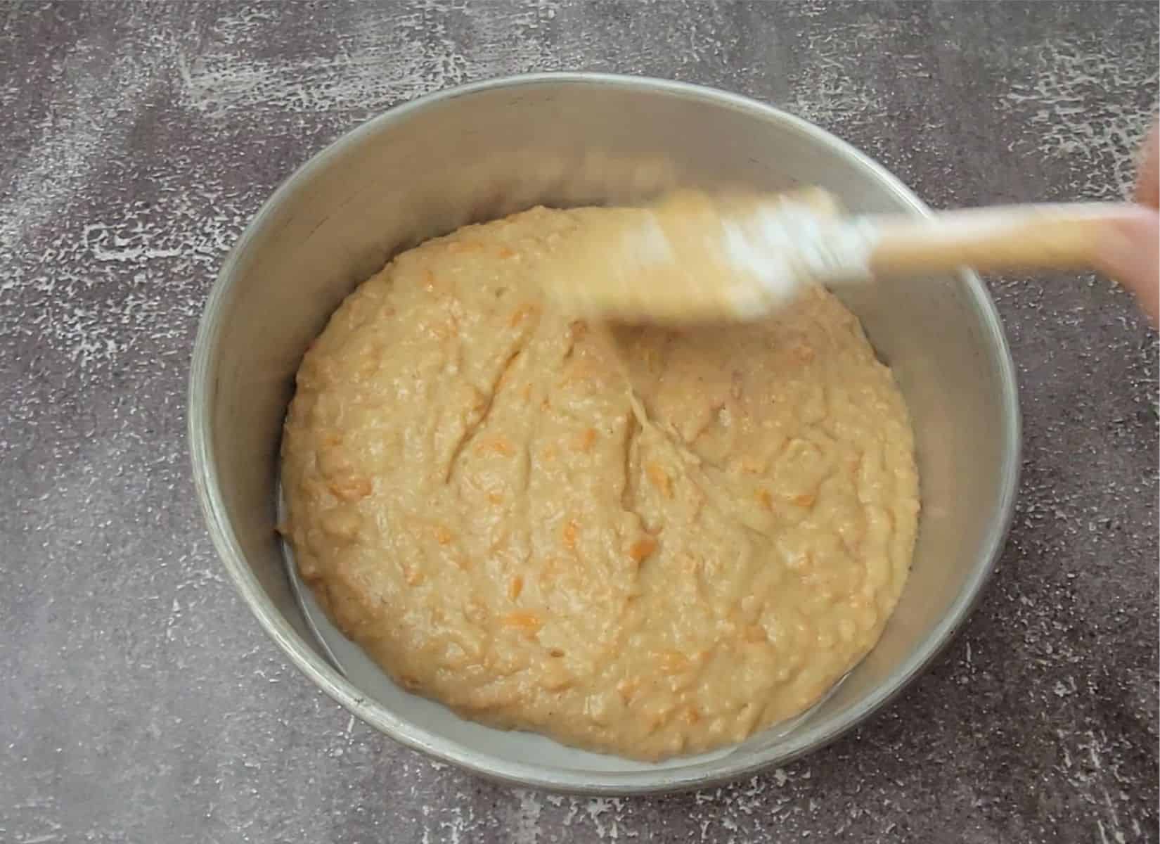 smoothing eggless carrot cake batter in baking pan prior to baking