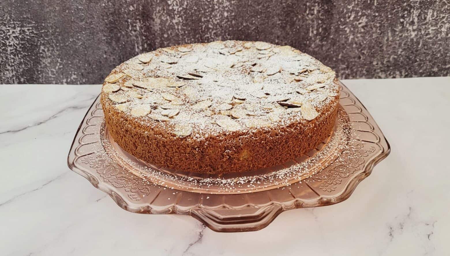 almond flour cake on a serving platter and dusted with powdered sugar