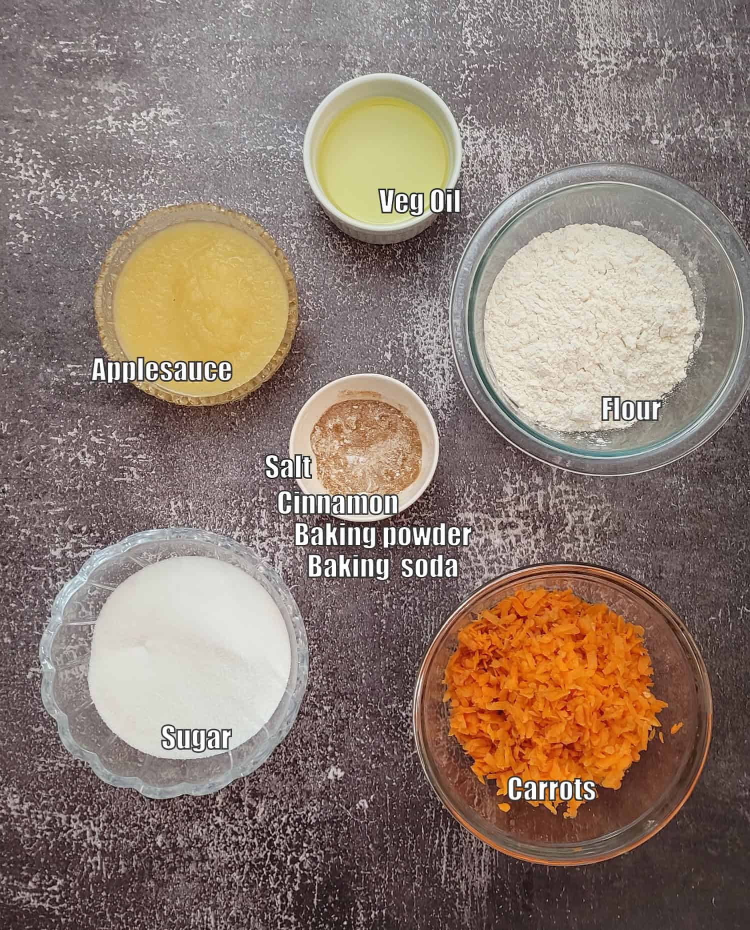 ingredients needed to make eggless carrot cake including shredded carrots, granulated sugar, baking soda, baking powder, salt, cinnamon, vegetable oil, applesauce and flour