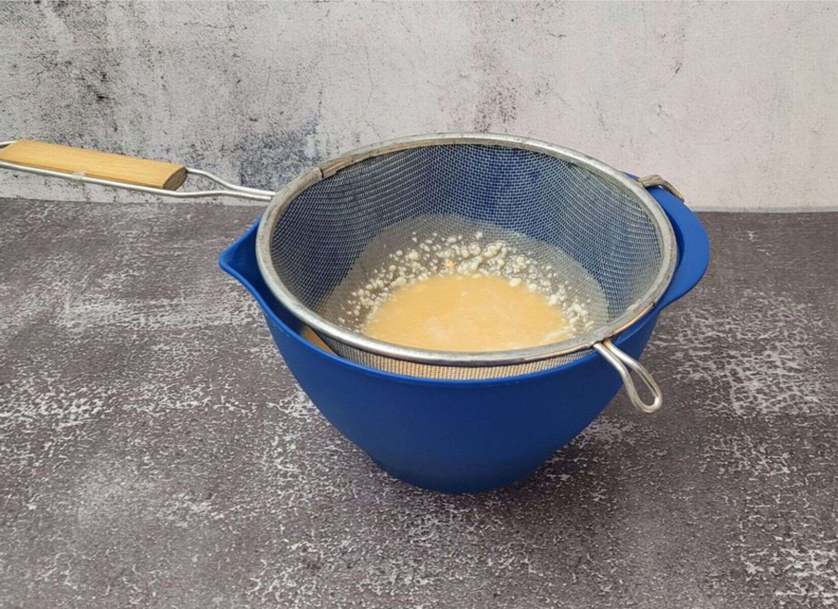 mirror glaze being strained through a sieve to remove any large pieces of white chocolate