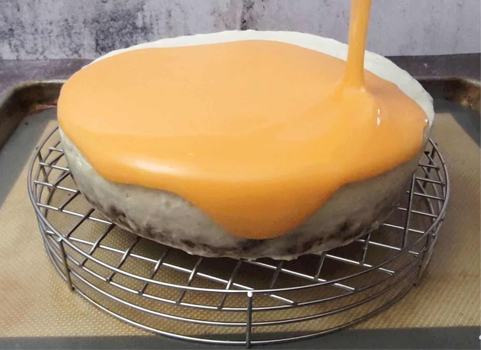 pouring mirror glaze over an eggless carrot cake with cream cheese mousse