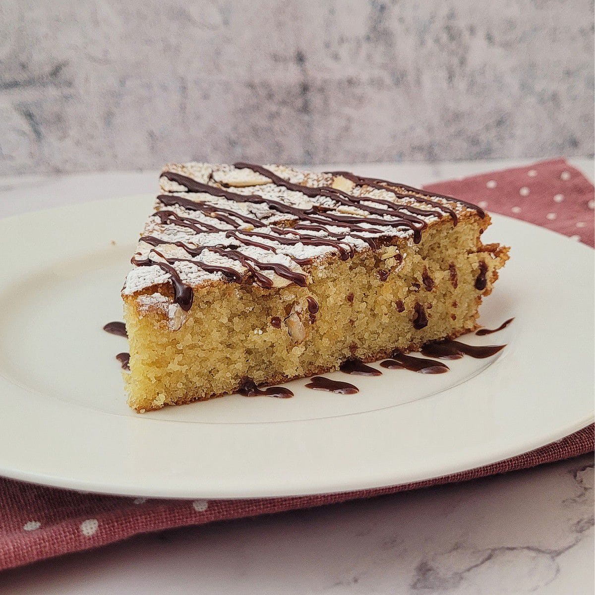 slice of almond flour cake on a plate and drizzled with chocolate sauce