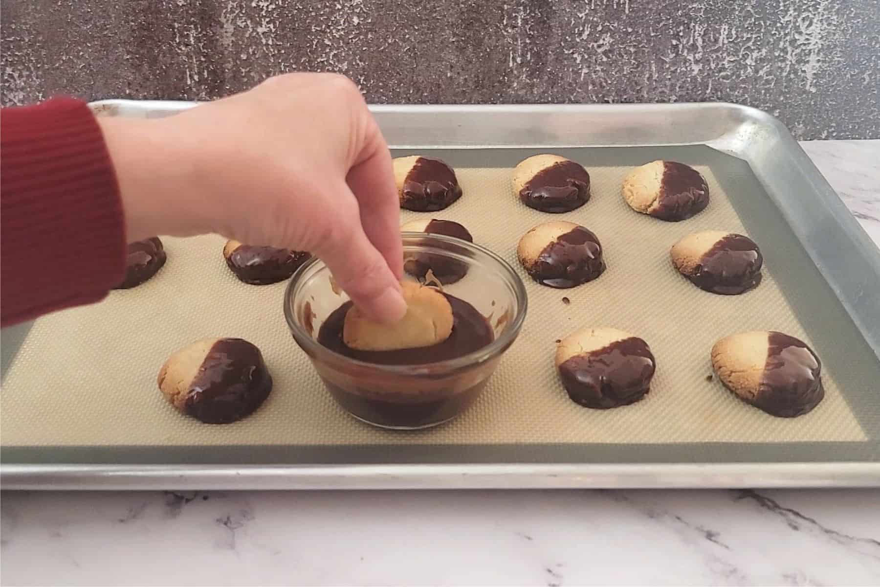 dunking gluten free almond flour cookies into melted chocolate