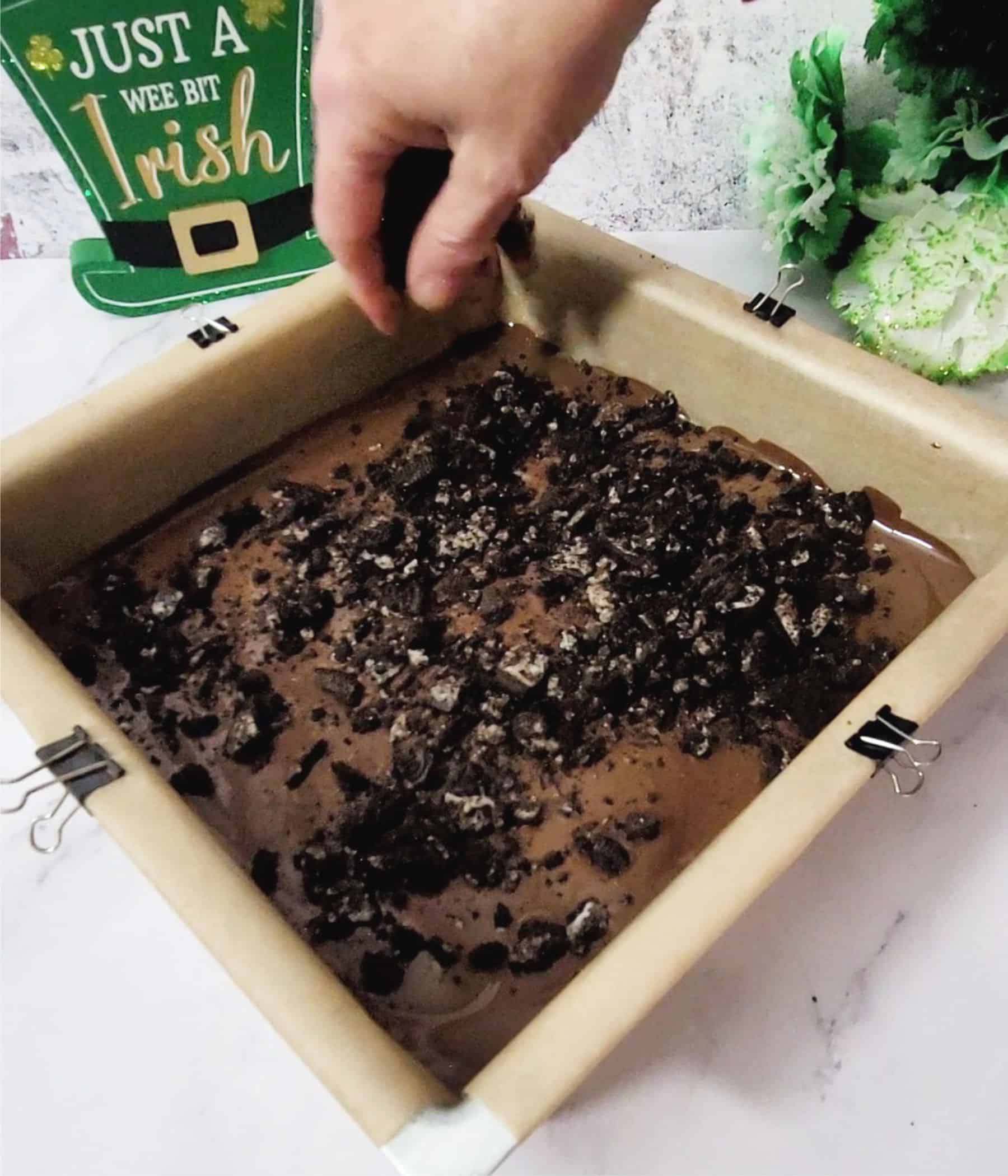 sprinkling crushed Oreos over melted chocolate to make Oreo bark recipe