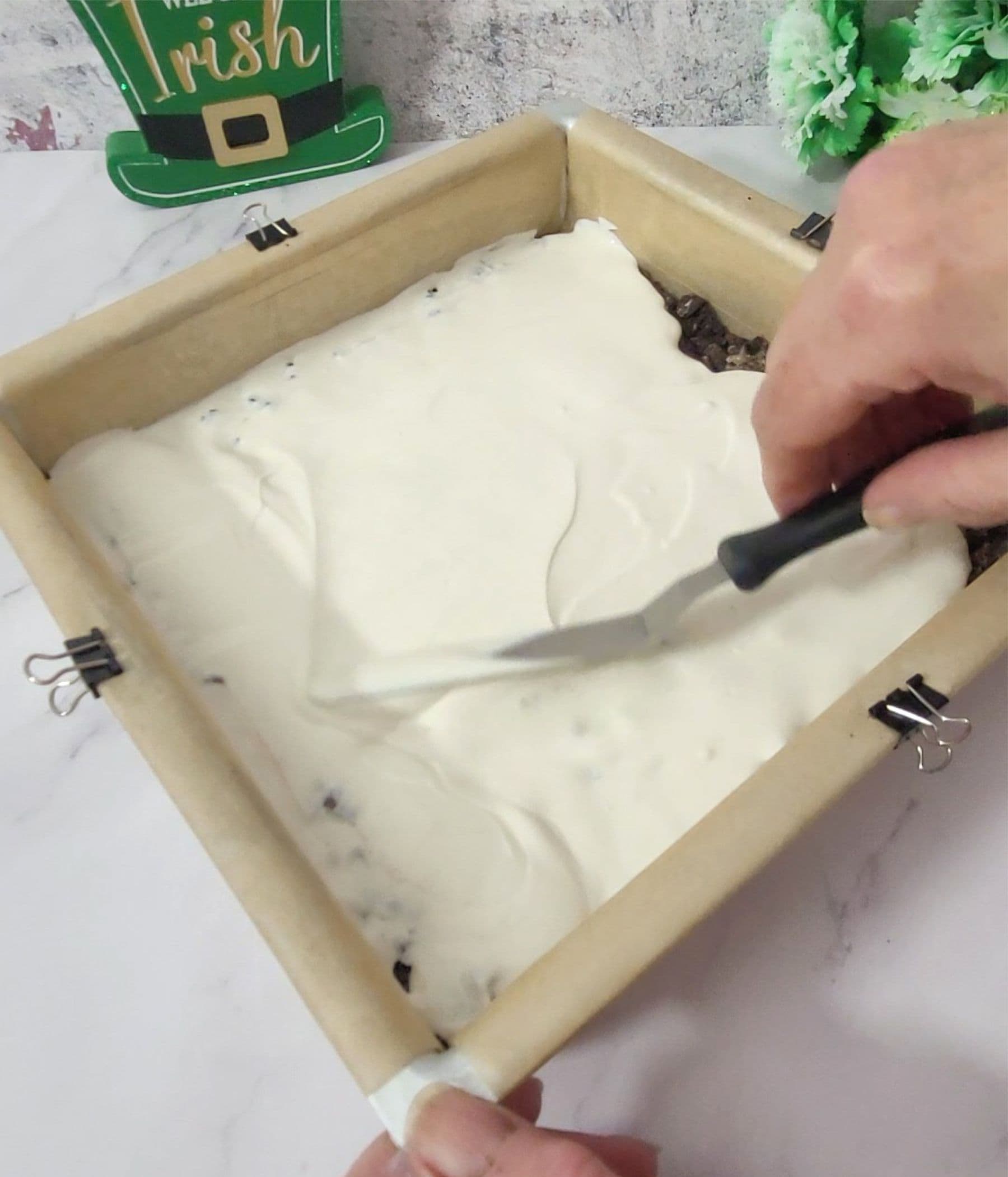 spreading white candy melts in pan over Oreos and chocolate