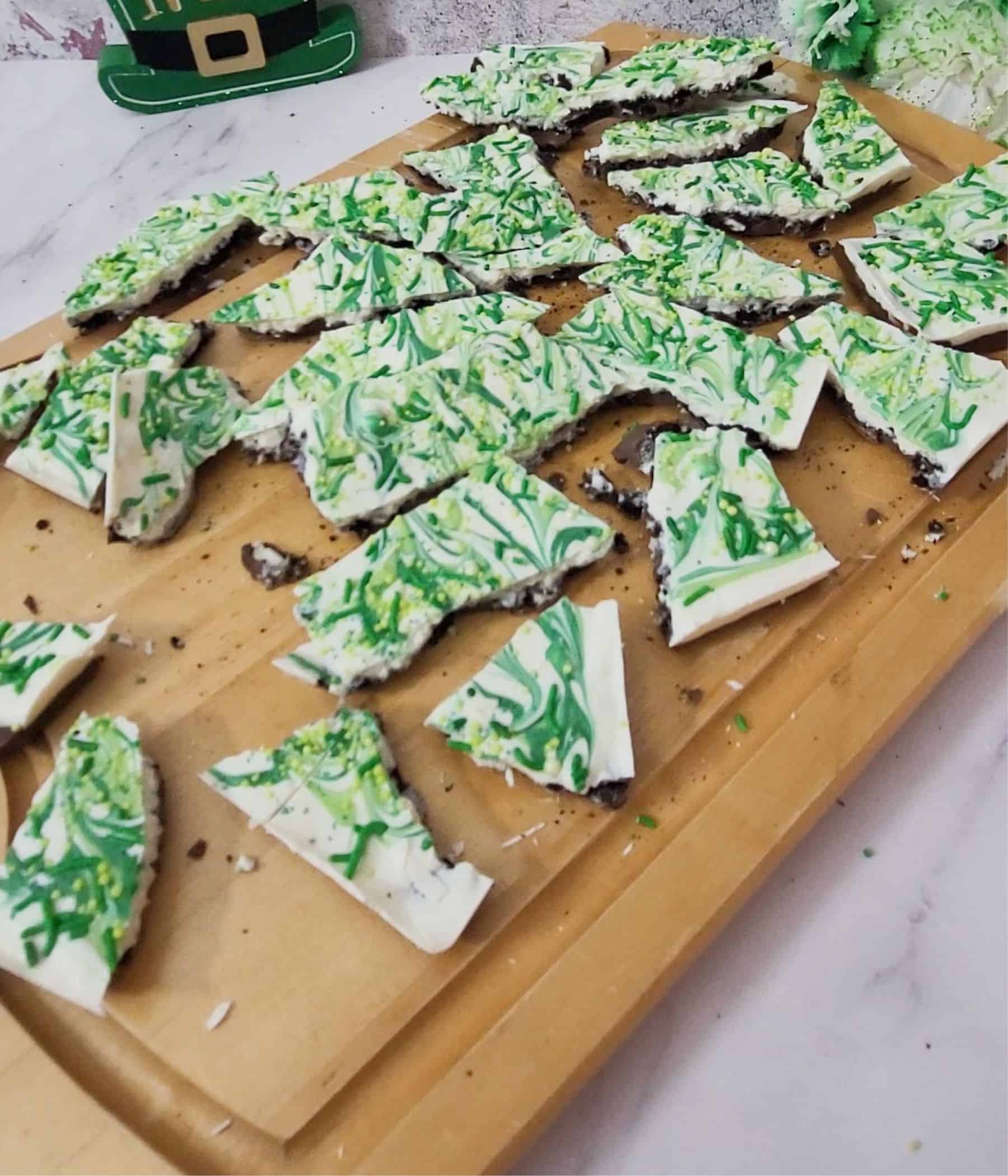 pieces of Oreo bark decorated for St. Patrick's Day on a wooden board