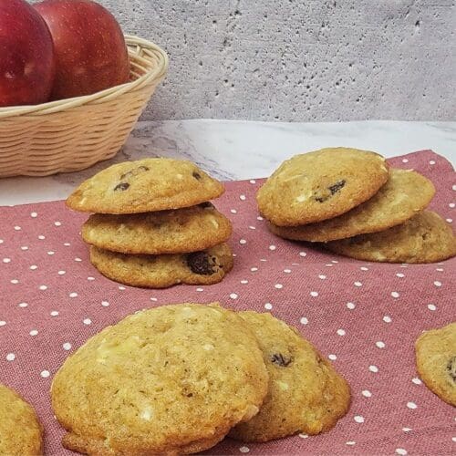 eggless apple cookies on a napkin with basket of apples in the background