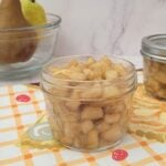 jar of homemade pear compote in a mason jar with pears in the background