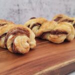 three puff pastry Nutella twists on a wooden serving board
