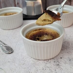 coffee crème brulee in a ramekin with a spoon digging into the custard