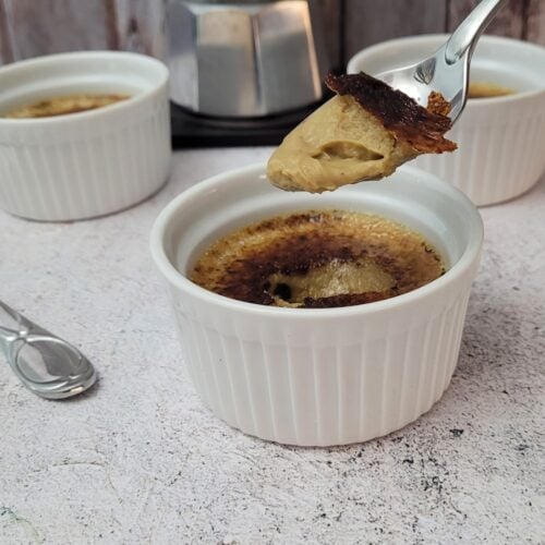 coffee crème brulee in a ramekin with a spoon digging into the custard