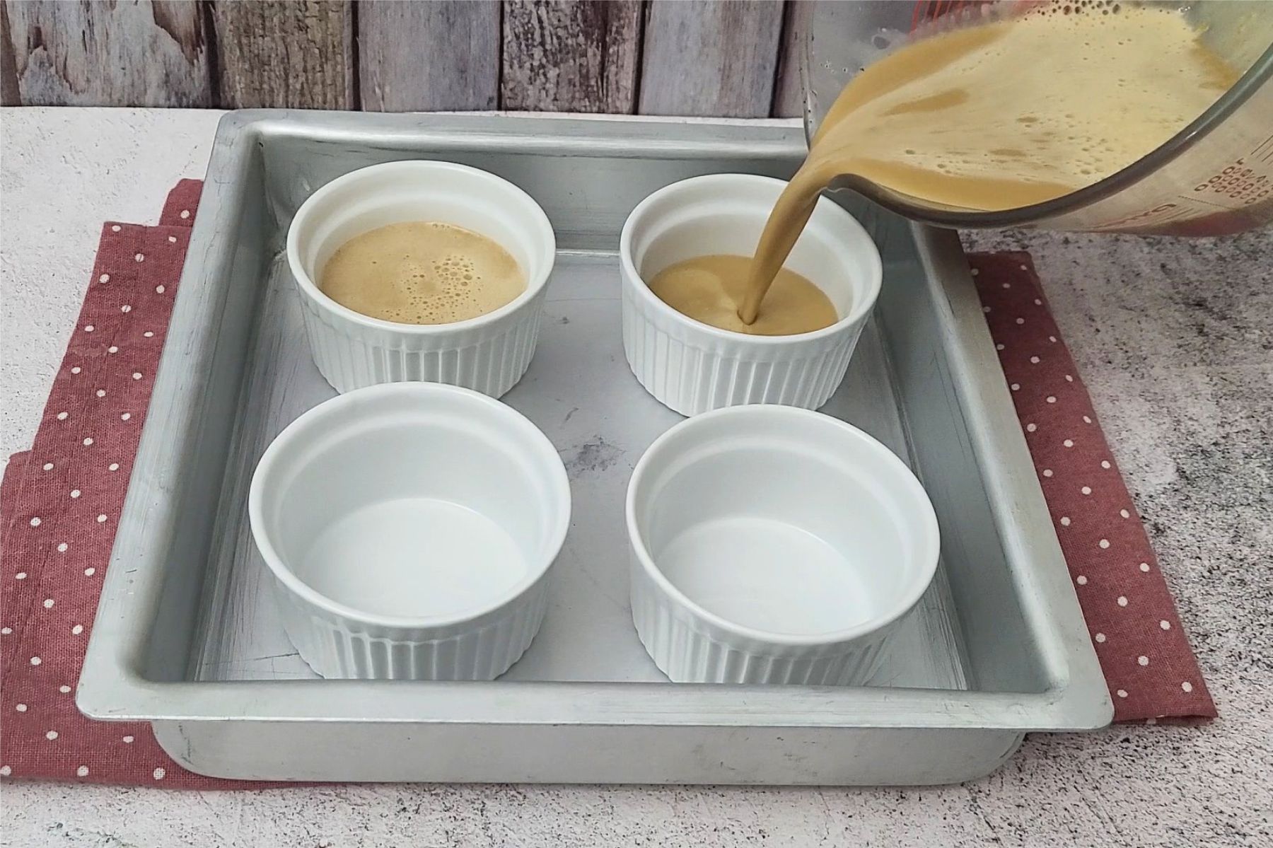 pouring coffee custard into ramekins to prepare for baking