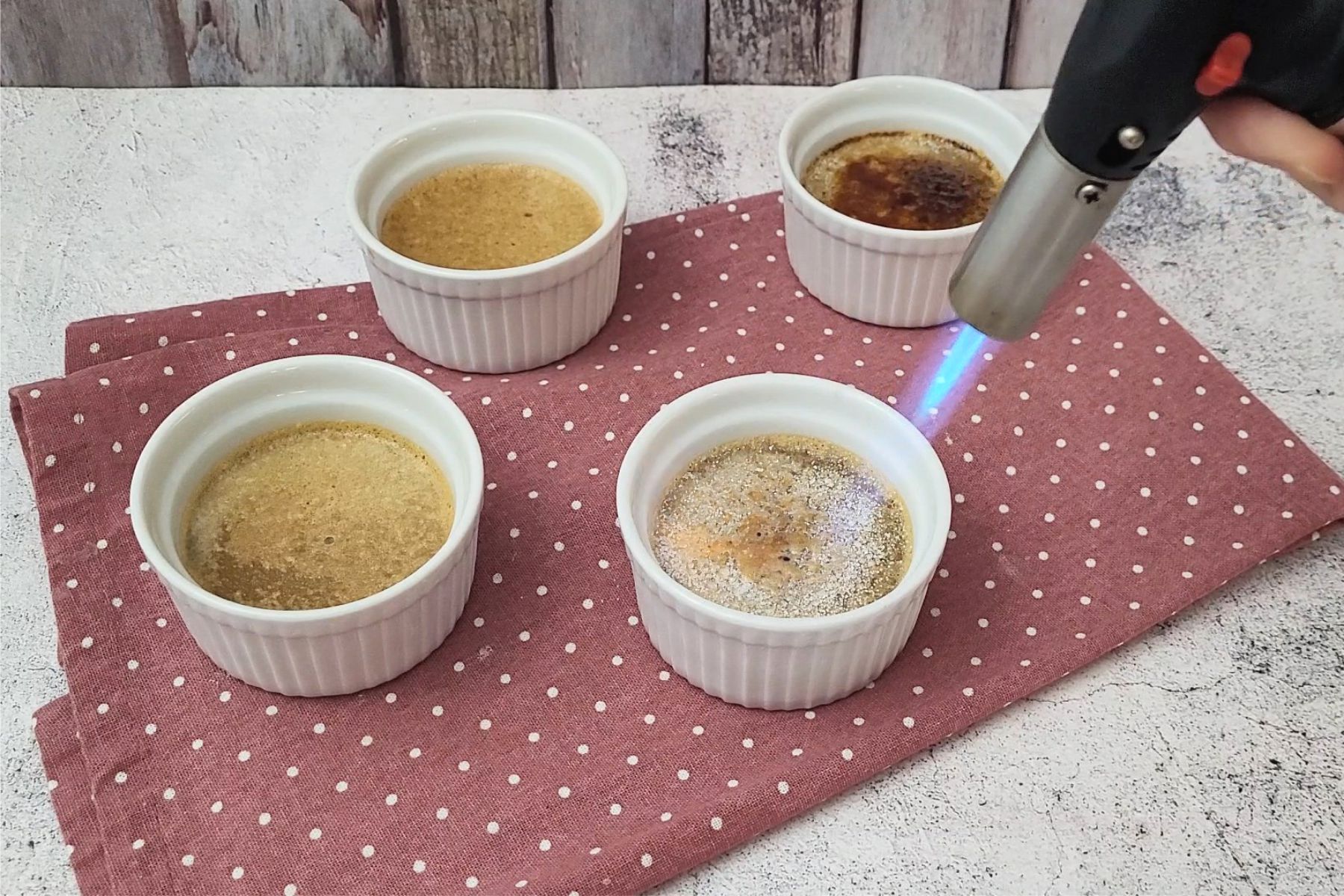 using a blow torch to brulee tops of custard dessert